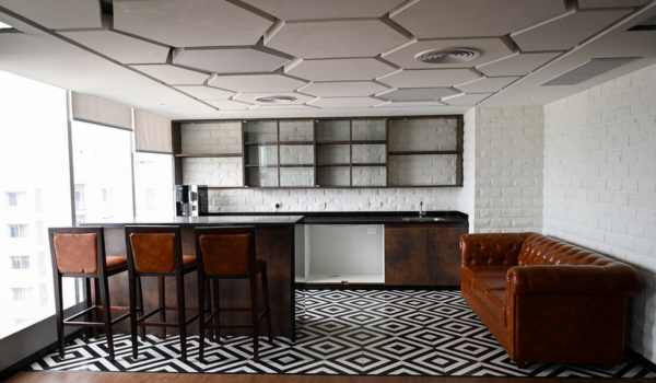 India flexible workspace lounge area with modern coworking pantry, bar seating, acoustic ceiling panels, and collaborative informal meeting space