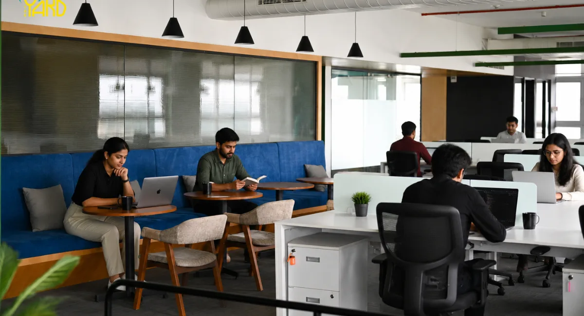 Modern managed office workspace with professionals working on laptops in a collaborative coworking environment featuring private workstations and lounge seating.