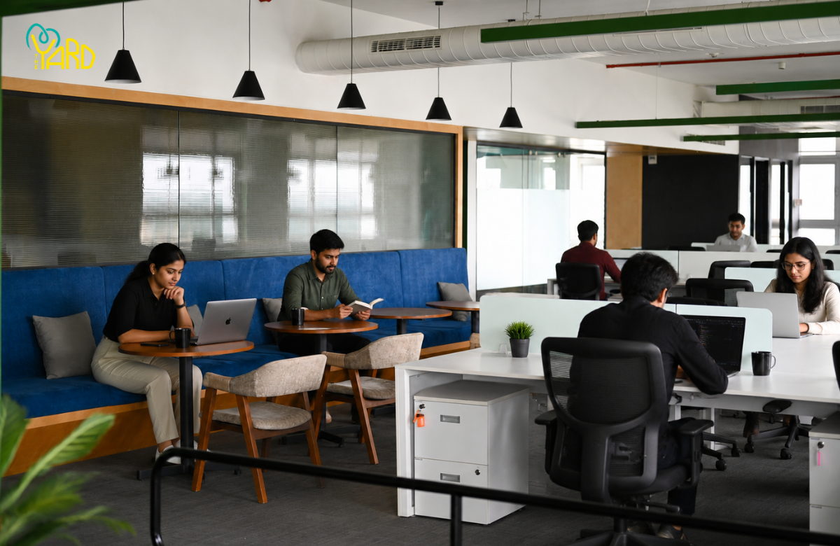 Modern managed office workspace with professionals working on laptops in a collaborative coworking environment featuring private workstations and lounge seating.