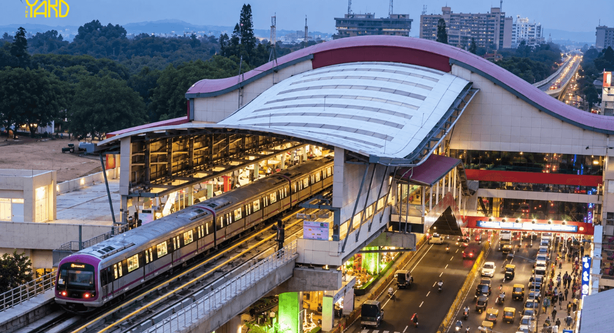 Namma Metro train arriving at a Bangalore metro station near heavy traffic