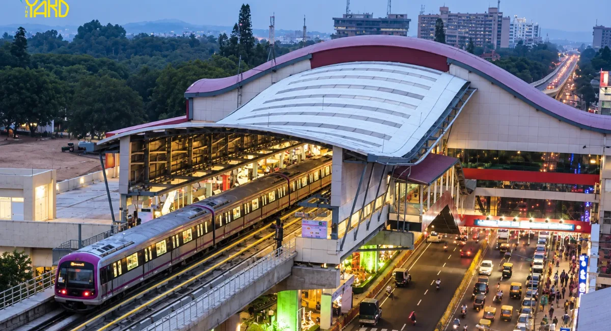 Namma Metro train arriving at a Bangalore metro station near heavy traffic