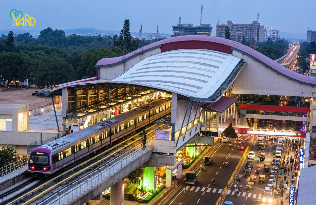 Namma Metro train arriving at a Bangalore metro station near heavy traffic