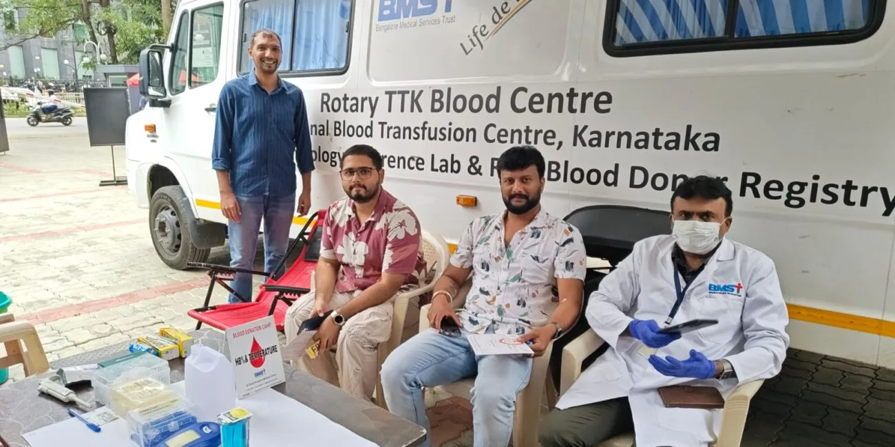 Volunteers and staff at The Yard's blood donation drive with the Rotary TTK Blood Centre mobile blood collection van, alongside donor screening equipment including a hemoglobin testing kit