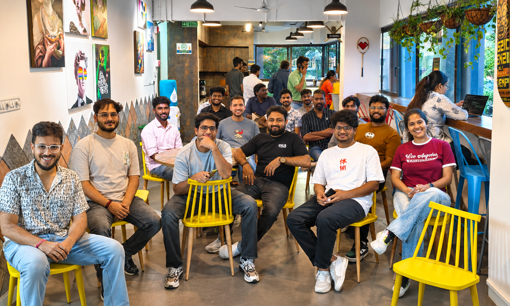 A group of professionals socializing in a vibrant coworking space with colourful seating and wall art