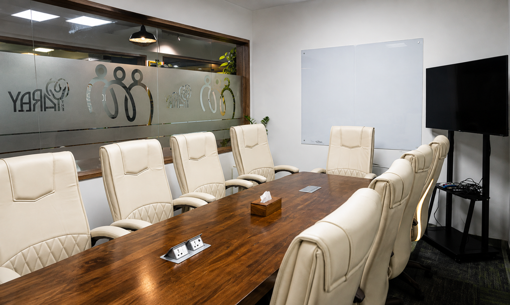 Meeting room with wooden table, leather chairs, whiteboard and TV for client meetings at The Yard coworking space