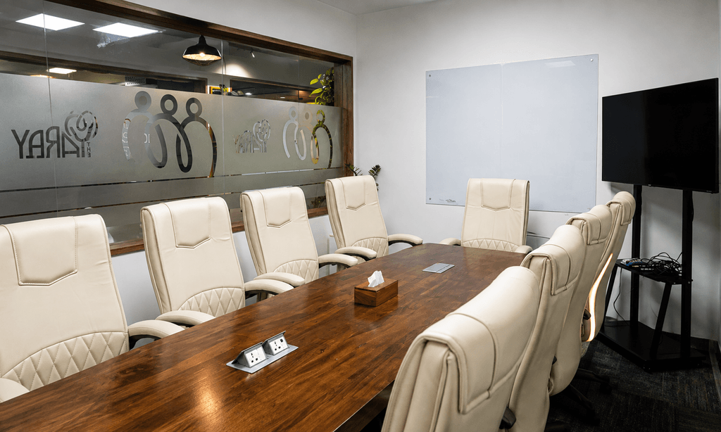 Meeting room with large wooden table and TV screen at The Yard coworking space