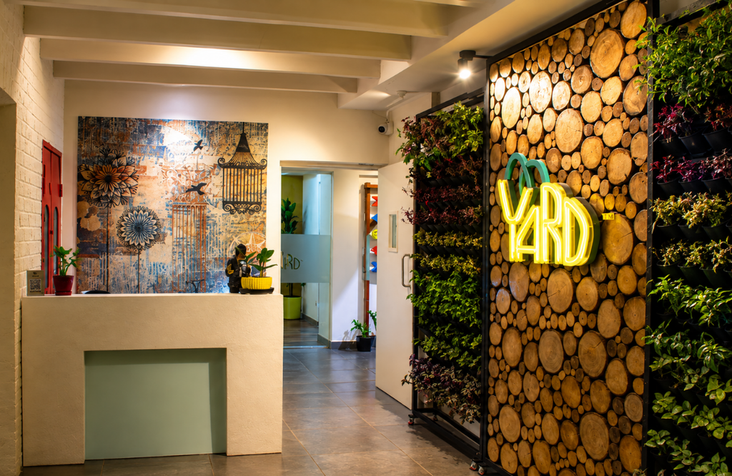 Reception desk with neon Yard sign, plant wall and security camera at The Yard coworking space