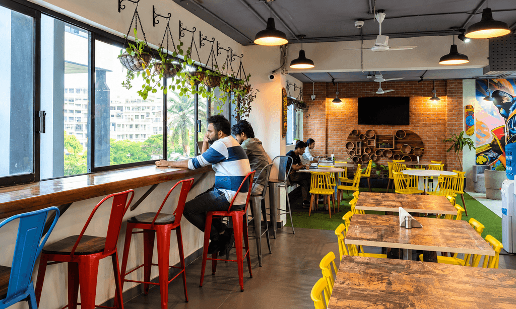Cafeteria and breakout seating area with plants and window bar seating at The Yard coworking space