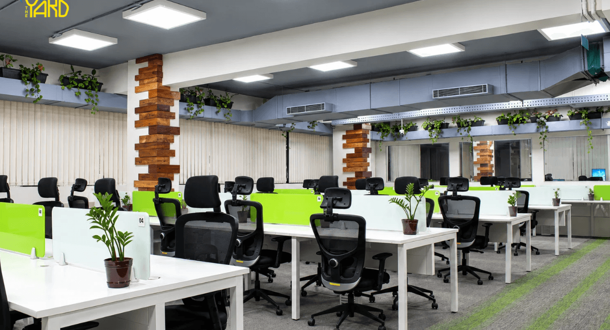 The Yard coworking space in Bangalore with shared office desks, ergonomic chairs, and green desk partitions