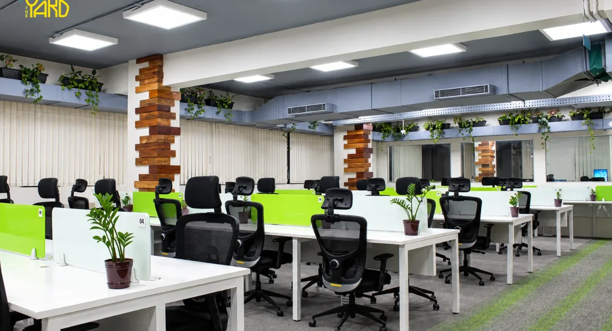 The Yard coworking space in Bangalore with shared office desks, ergonomic chairs, and green desk partitions