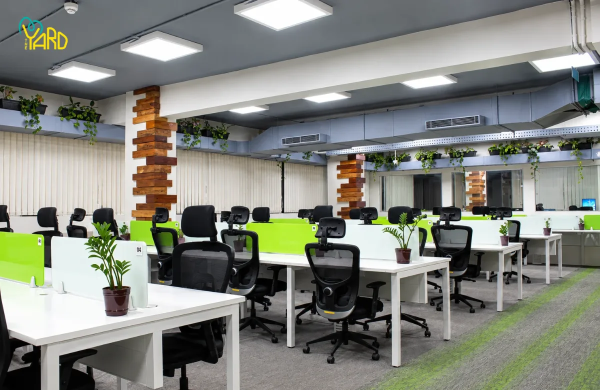 The Yard coworking space in Bangalore with shared office desks, ergonomic chairs, and green desk partitions