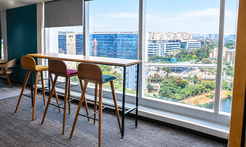 Coworking workspace with a high counter, bar stools and large windows overlooking Bengaluru's commercial district